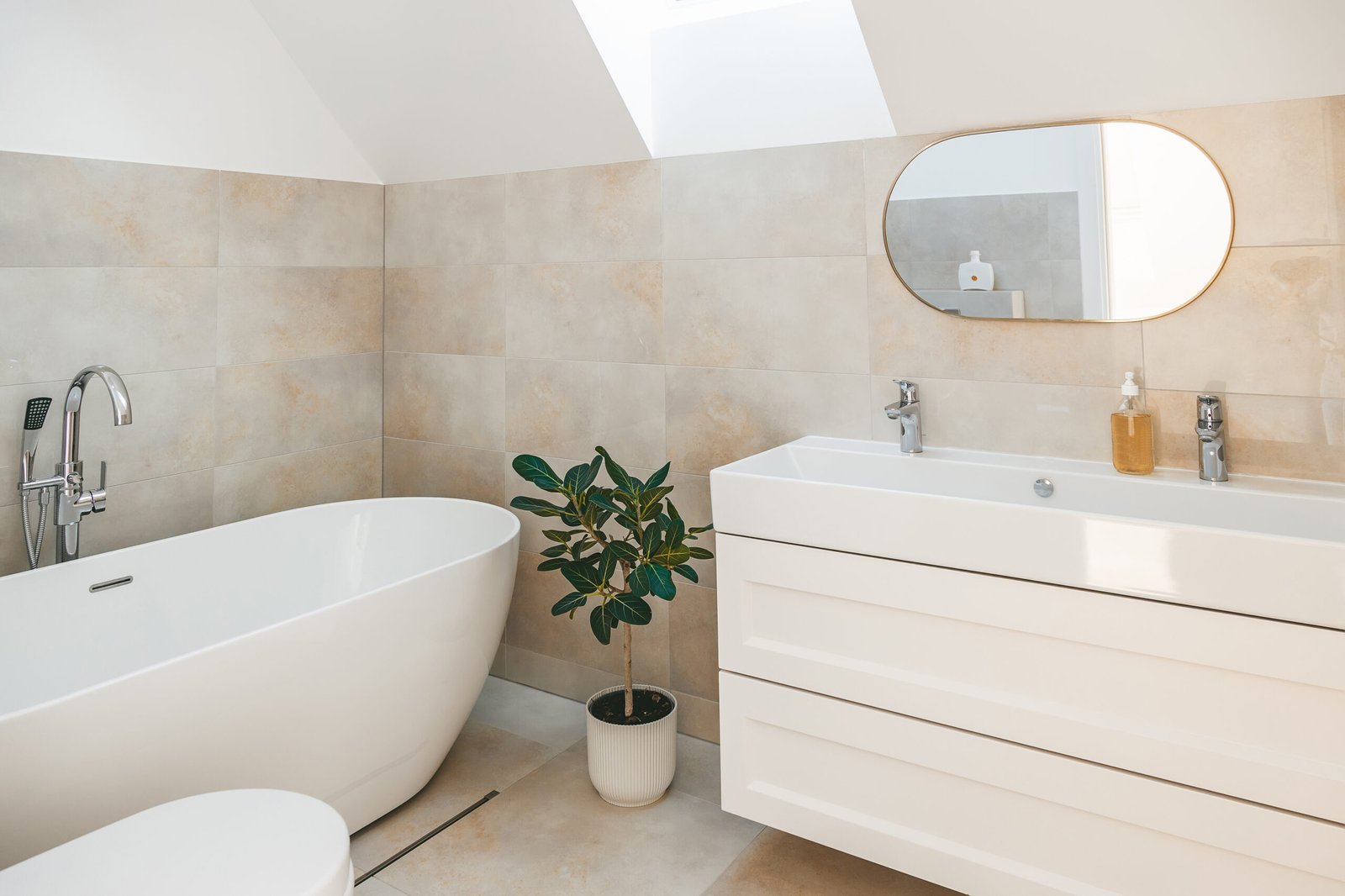 A minimalistic bathroom with standalone bathtub and shower, long sink and mirror, and ficus plant